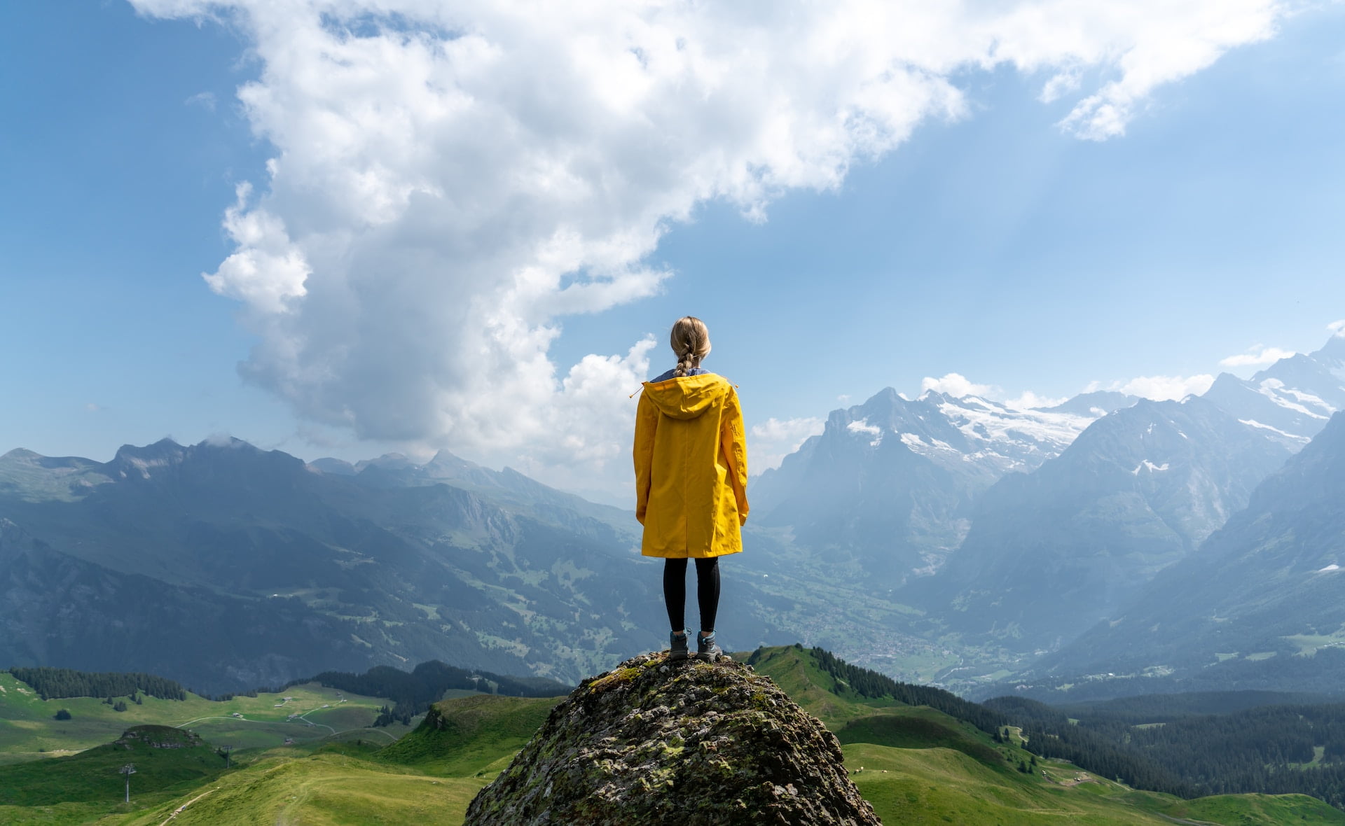 A person standing on a mountaintop feeling freedom overlooking a vast open landscape.