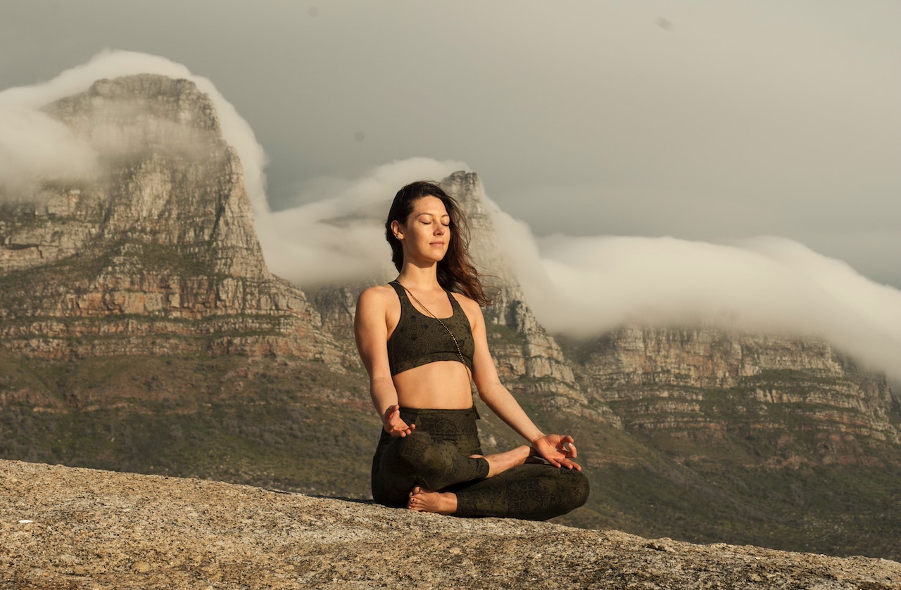 A person meditating by a tranquil lake in a serene forest, symbolizing the practice of mindfulness for emotional well-being.