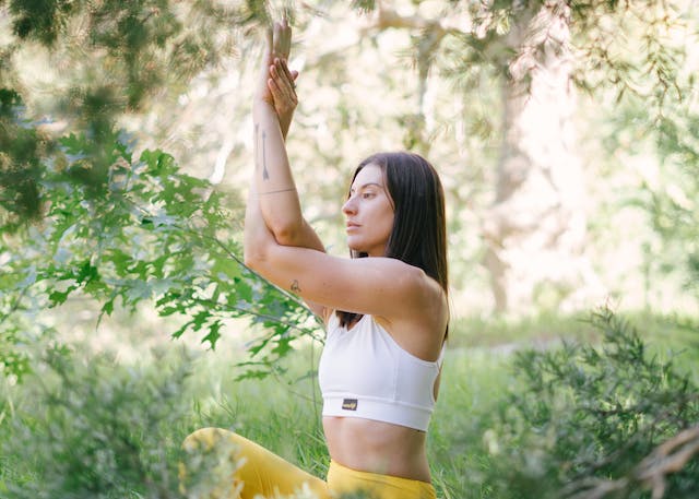 Woman meditating on a mountain, representing the concept of improved focus and concentration from mindfulness practices.