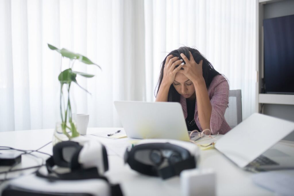 professional woman, overwhelmed, rubbing her temples at her desk.