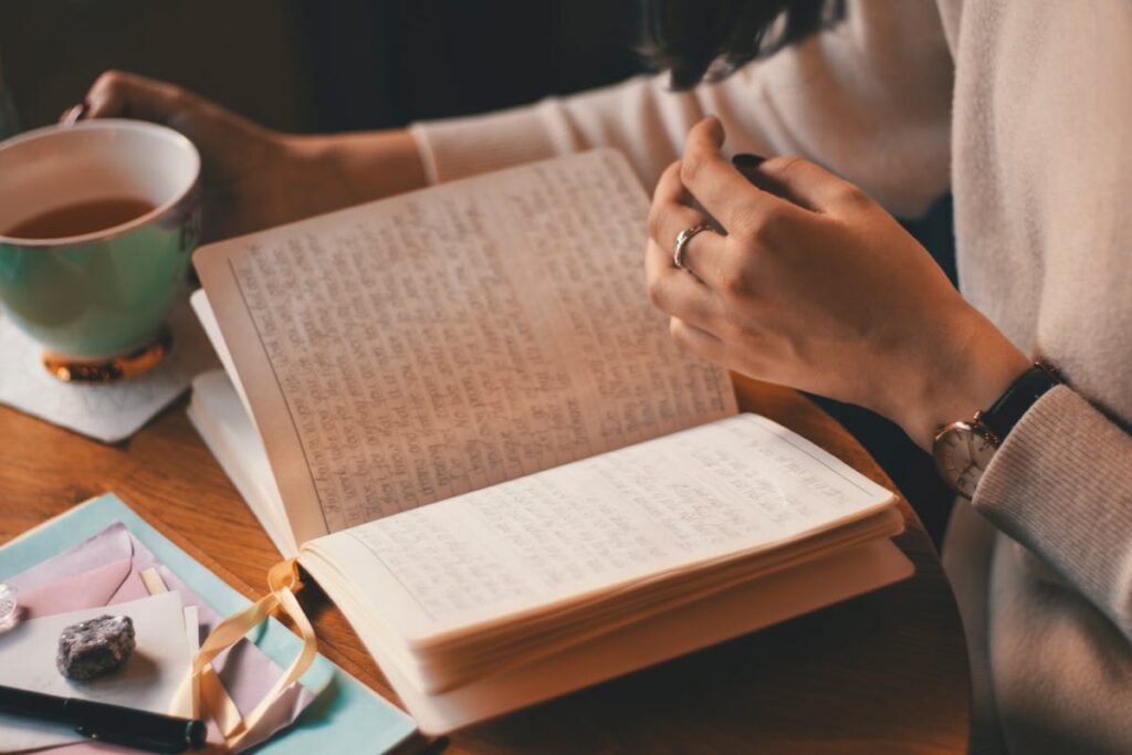 A professional sitting calmly with a cup of tea, journaling their daily affirmation.